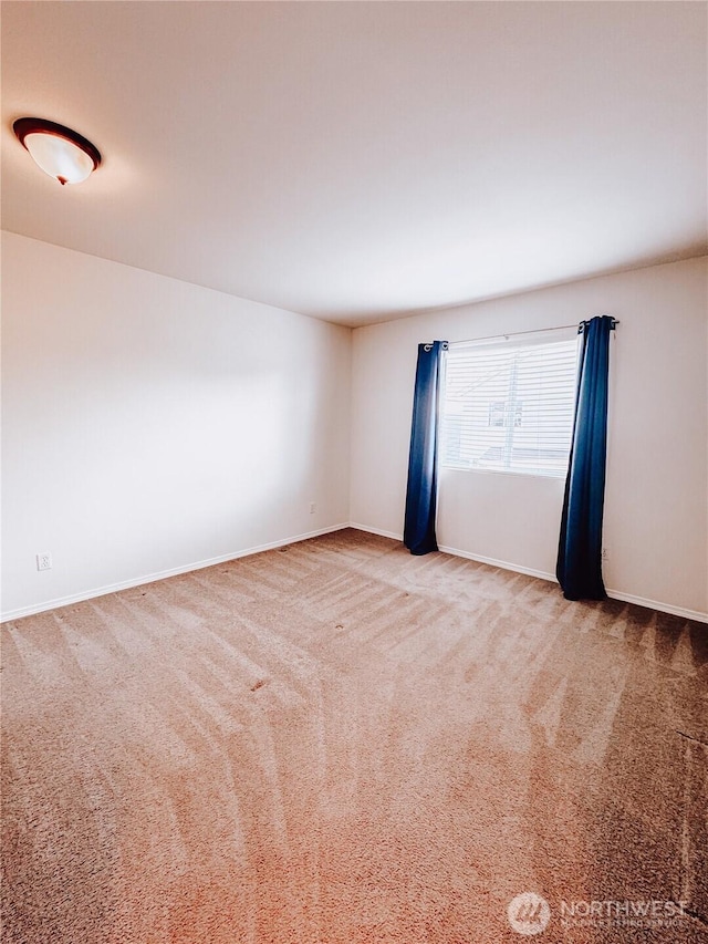 unfurnished room with carpet flooring and baseboards