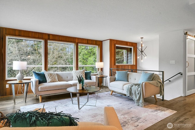 living room with wooden walls, wood finished floors, and a textured ceiling