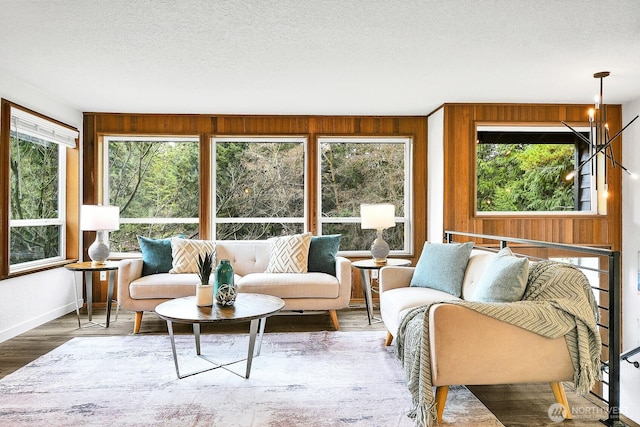 living area featuring baseboards, wood finished floors, a textured ceiling, and wood walls