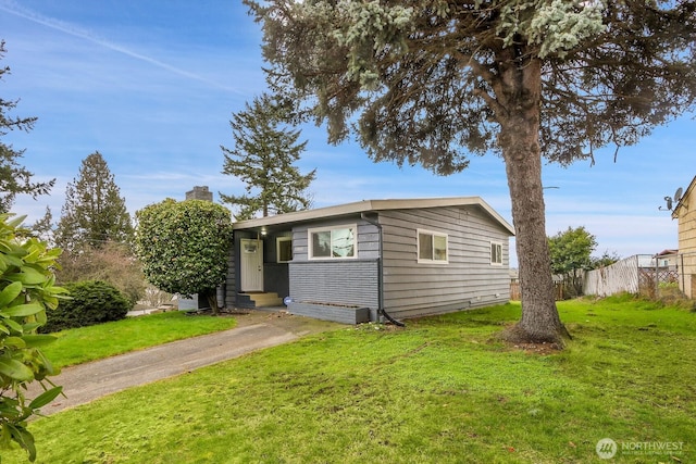 view of front of property featuring fence, entry steps, a front yard, a chimney, and driveway