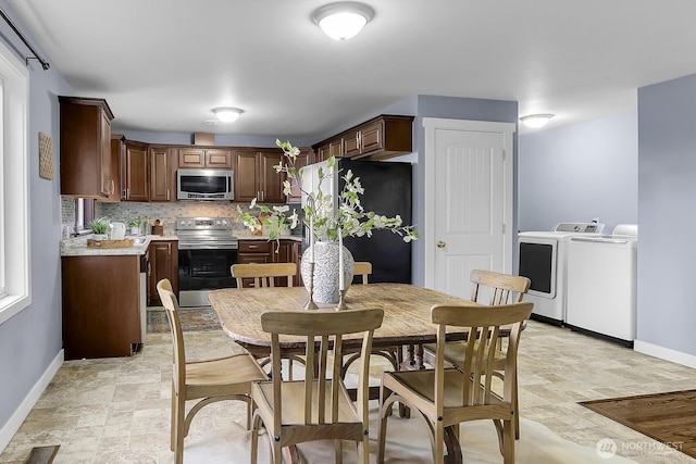 dining area featuring visible vents, washing machine and dryer, stone finish flooring, and baseboards