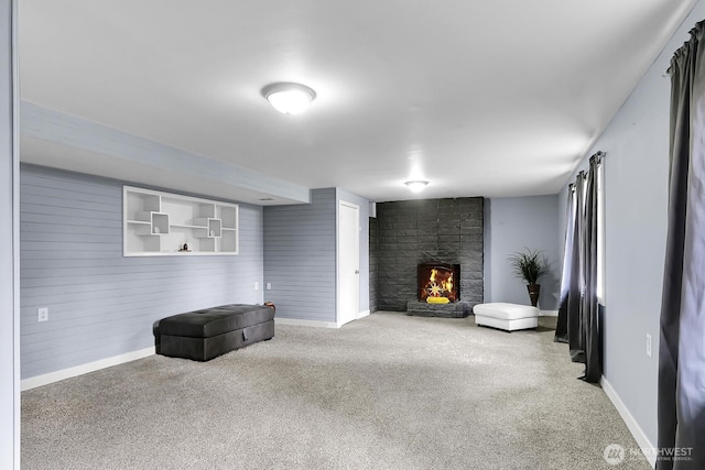 living area with baseboards, a large fireplace, and carpet flooring