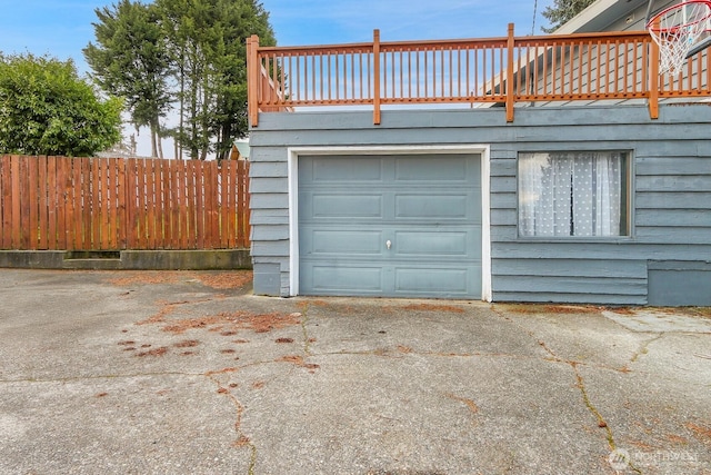 garage featuring driveway and fence