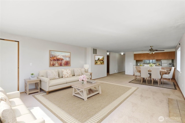 living room featuring visible vents, light colored carpet, and a ceiling fan