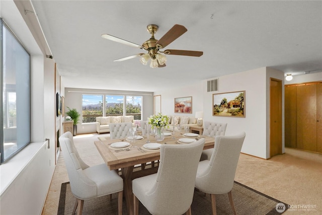 dining space featuring light carpet, visible vents, and ceiling fan