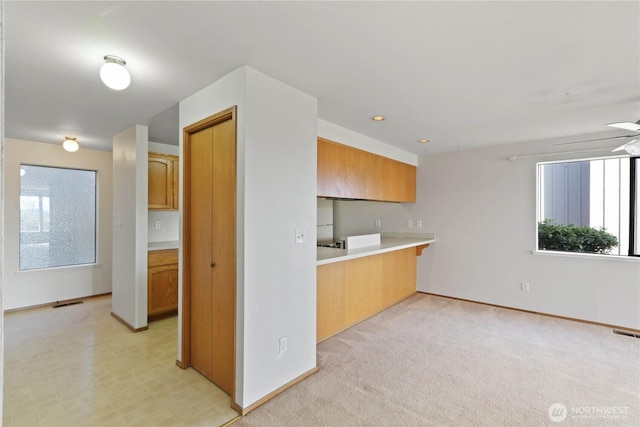 kitchen featuring visible vents, baseboards, ceiling fan, and light countertops