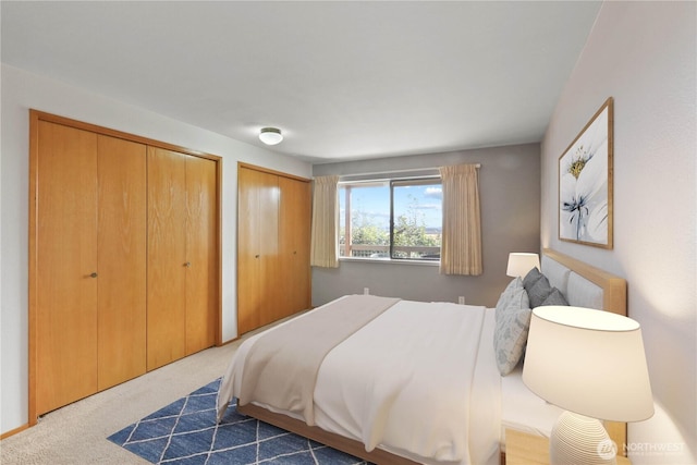 bedroom featuring dark carpet and two closets