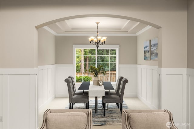 dining space with light carpet, a chandelier, wainscoting, and a tray ceiling