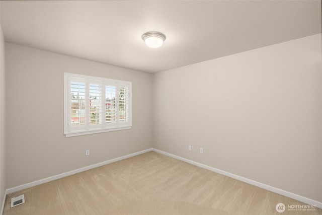 empty room with baseboards, visible vents, and light carpet