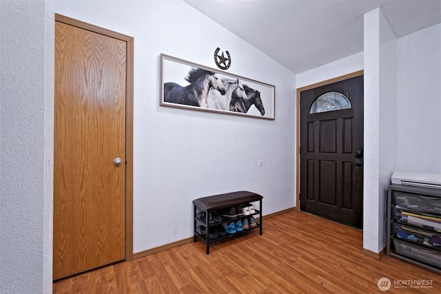 entrance foyer with light wood-style flooring, baseboards, and vaulted ceiling