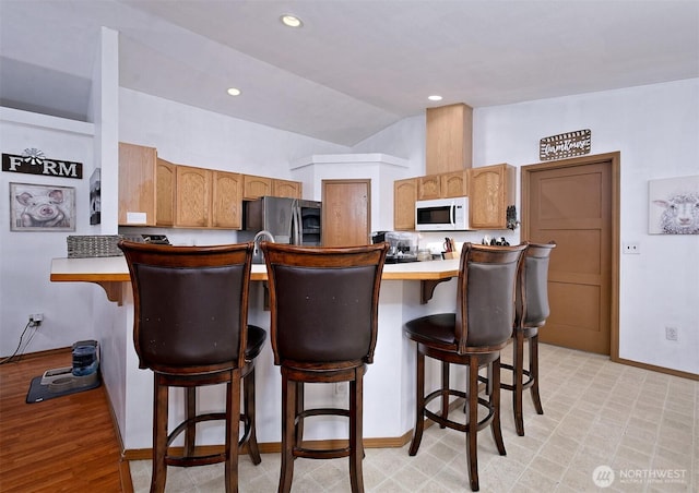 kitchen featuring white microwave, light countertops, vaulted ceiling, smart refrigerator, and a kitchen bar