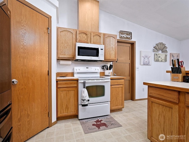 kitchen featuring baseboards, white appliances, lofted ceiling, and light countertops