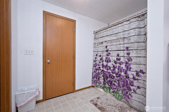 full bath featuring curtained shower and baseboards