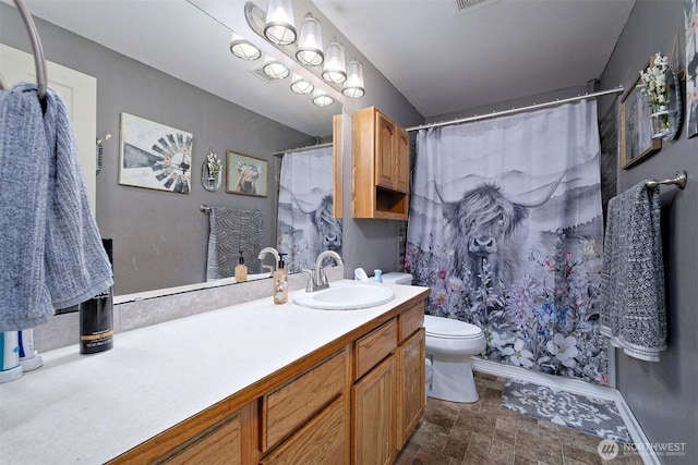 bathroom featuring a shower with curtain, toilet, vanity, and stone finish floor