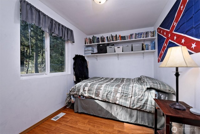 bedroom featuring visible vents, baseboards, and wood finished floors