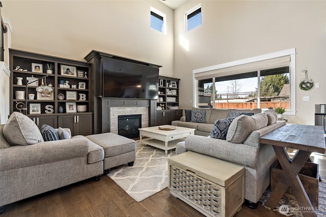 living room featuring a high ceiling, wood finished floors, and a fireplace