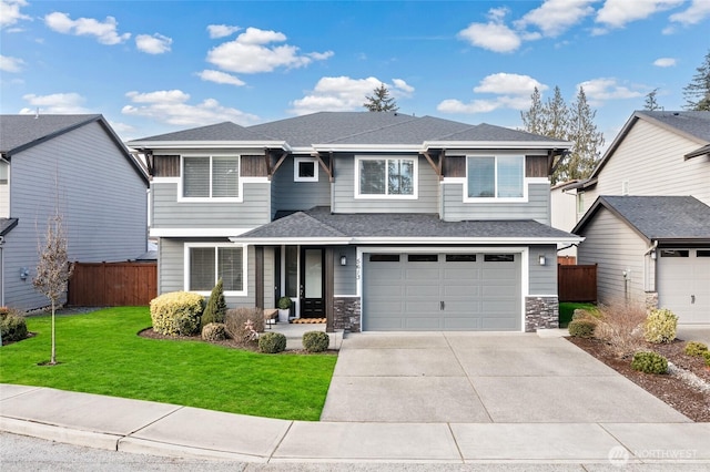 prairie-style home with driveway, fence, roof with shingles, a front yard, and a garage