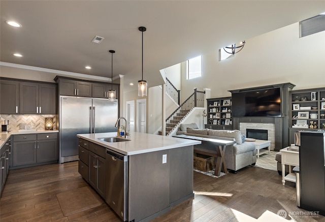 kitchen featuring a sink, a stone fireplace, light countertops, and stainless steel appliances