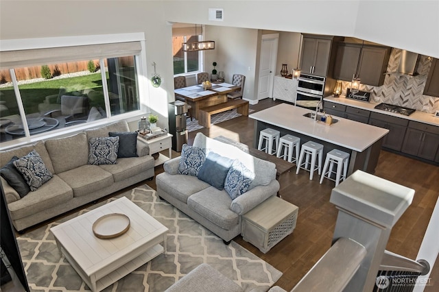 living room featuring a notable chandelier, visible vents, and dark wood-type flooring