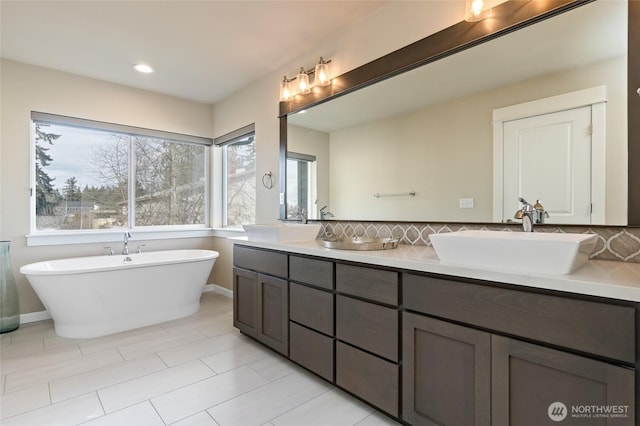 full bathroom featuring a sink, tasteful backsplash, and a freestanding bath