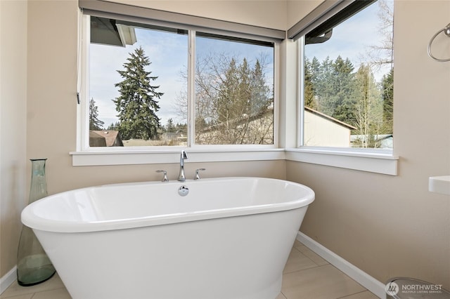 bathroom featuring tile patterned floors, a freestanding bath, and baseboards