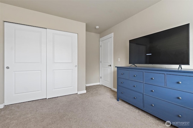 unfurnished bedroom featuring light colored carpet, baseboards, and a closet