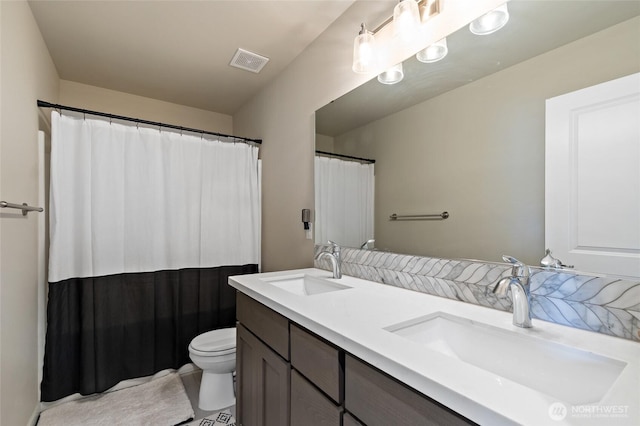 bathroom featuring double vanity, toilet, visible vents, and a sink