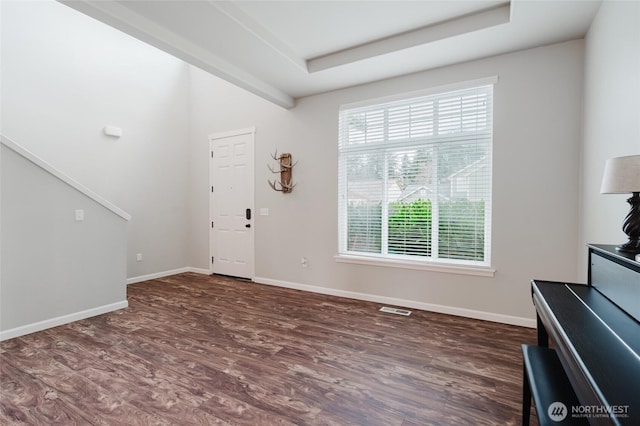 foyer entrance featuring a raised ceiling, baseboards, visible vents, and dark wood-style flooring