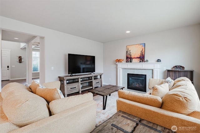 living area with a glass covered fireplace, recessed lighting, and baseboards