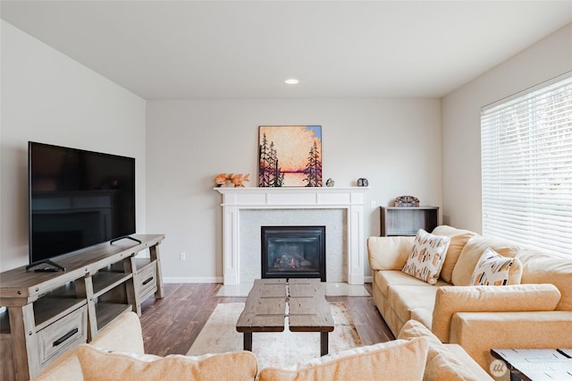 living area featuring a fireplace with flush hearth, recessed lighting, baseboards, and wood finished floors