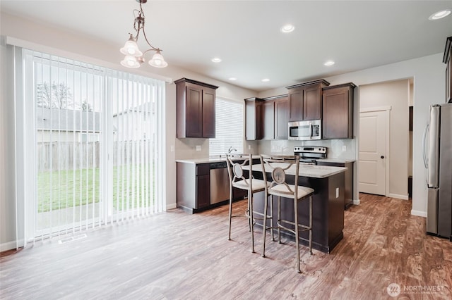 kitchen featuring tasteful backsplash, dark brown cabinetry, appliances with stainless steel finishes, and a kitchen island