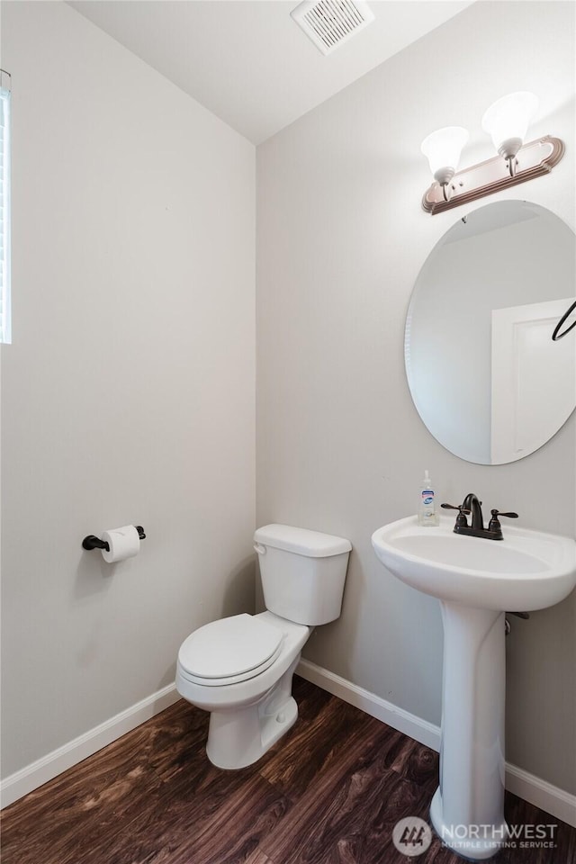 bathroom featuring visible vents, toilet, a sink, wood finished floors, and baseboards