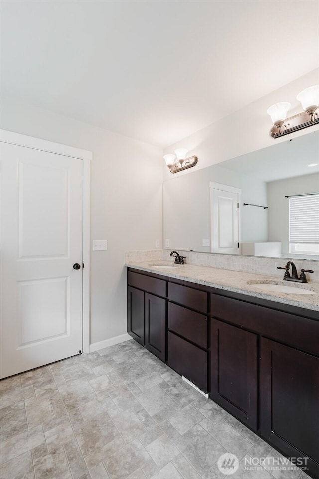 full bathroom with a sink, baseboards, and double vanity