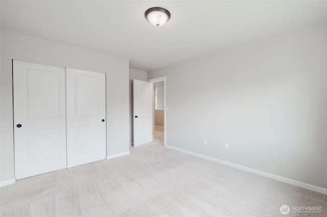 unfurnished bedroom featuring a closet, baseboards, and light colored carpet