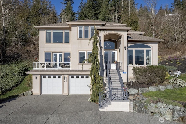 view of front of house featuring stucco siding, an attached garage, concrete driveway, and a balcony