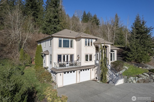 view of front of home featuring aphalt driveway, a garage, a balcony, and stucco siding