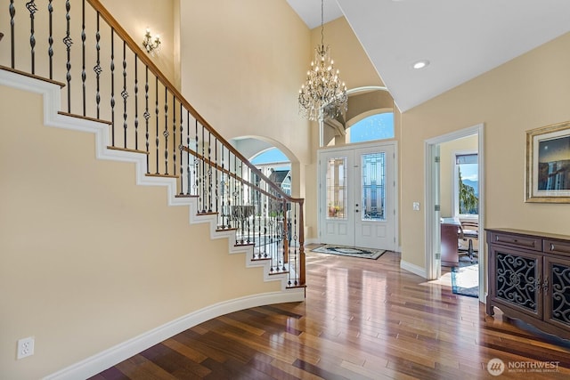 foyer entrance with a notable chandelier, plenty of natural light, baseboards, and wood-type flooring