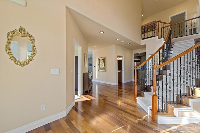 entryway with recessed lighting, a high ceiling, baseboards, and wood finished floors