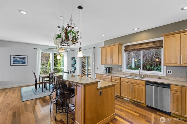 kitchen featuring stainless steel dishwasher, dark wood-type flooring, a breakfast bar area, and a sink