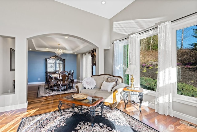 living room featuring wood finished floors, plenty of natural light, visible vents, and arched walkways