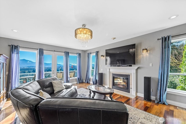 living area featuring a wealth of natural light, visible vents, a tile fireplace, and wood finished floors