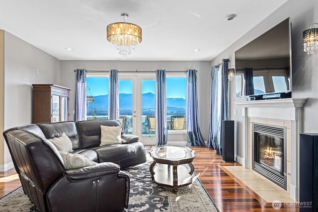 living room with wood finished floors, baseboards, an inviting chandelier, a fireplace with flush hearth, and recessed lighting