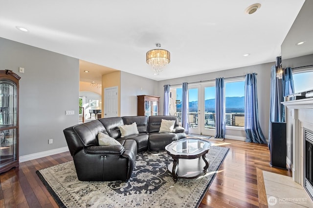 living room featuring baseboards, a chandelier, a fireplace with flush hearth, hardwood / wood-style floors, and recessed lighting