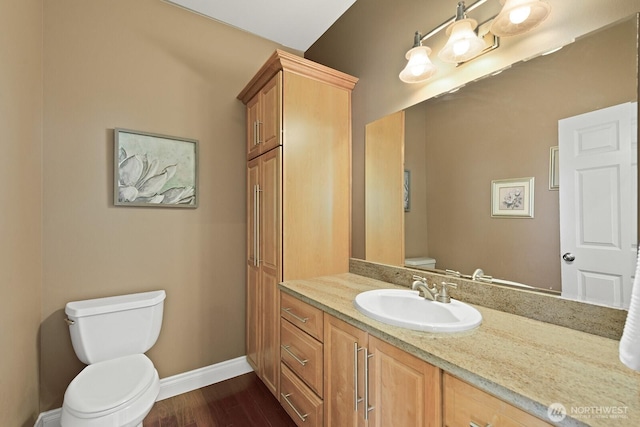 bathroom featuring vanity, toilet, wood finished floors, and baseboards