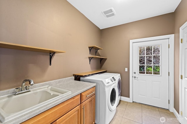 laundry area featuring baseboards, washer and clothes dryer, light tile patterned floors, cabinet space, and a sink