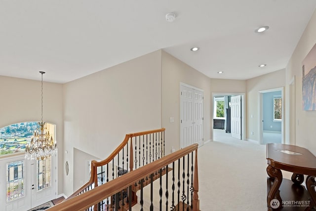 hallway with an upstairs landing, recessed lighting, carpet, an inviting chandelier, and baseboards