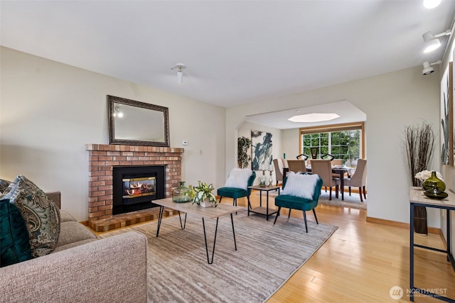 living room featuring light wood-type flooring, baseboards, and a fireplace