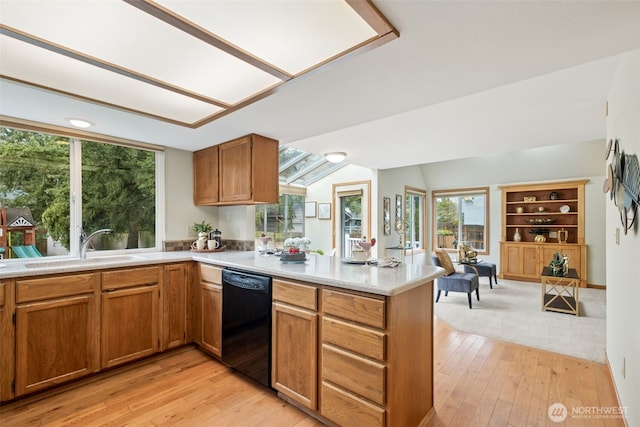 kitchen with light wood finished floors, a peninsula, a sink, light countertops, and dishwasher