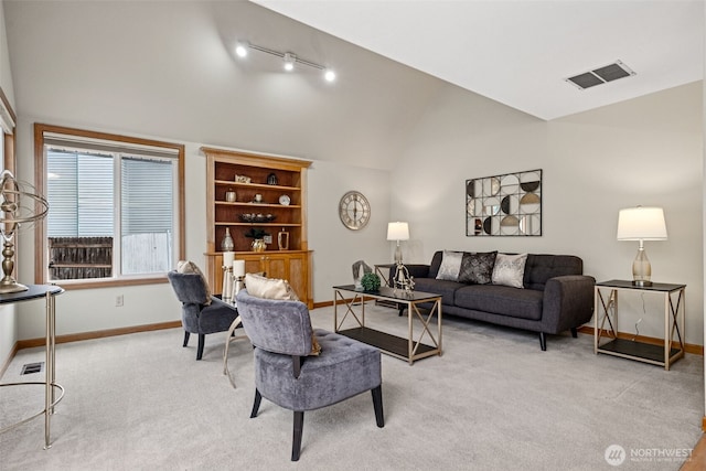 living room with visible vents, baseboards, lofted ceiling, rail lighting, and light colored carpet