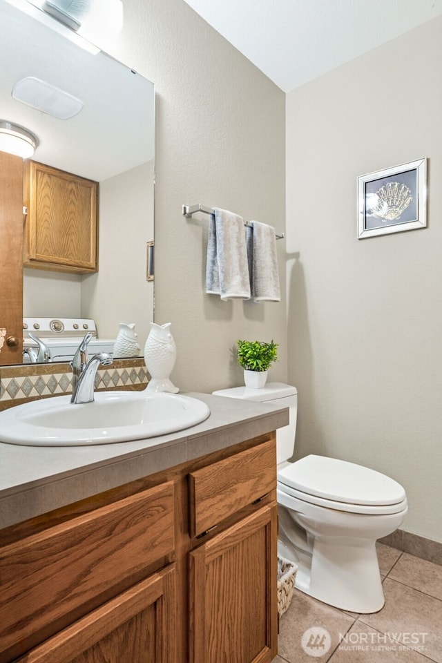 bathroom with tile patterned floors, toilet, vanity, and washer and dryer